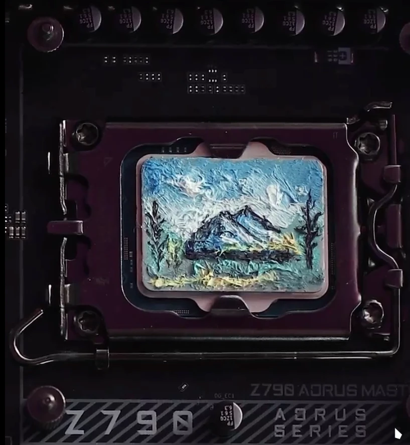 The image shows a beautiful landscape painting. There's a mountain range surrounded by some trees on a sunny day. Blue sky. Just a hint of cloud. Oh and it's all painted on a CPU as if it was thermal paste