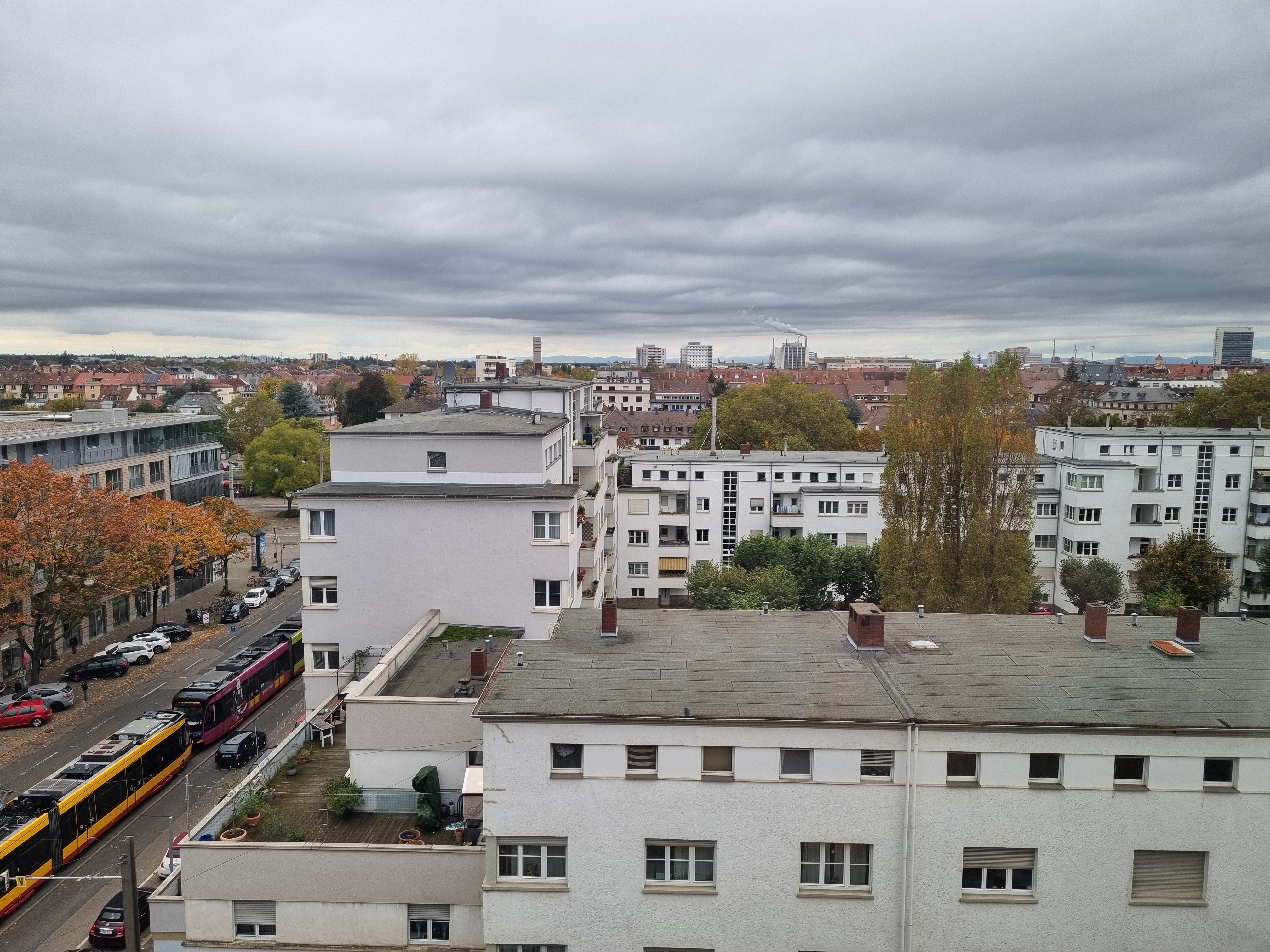 Ausblick über eine Stadt. Fotografiert aus höherer Position. Am linken Rand fährt eine Bahn, einzelne Hochhäuser sind zu erkennnen