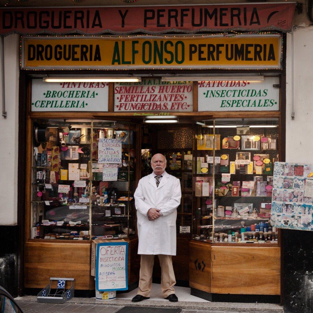 A man - presumably Alfonso - standing in front of his drug store in Bilbao in the Spanish Basque country. He looks proud of his shop.