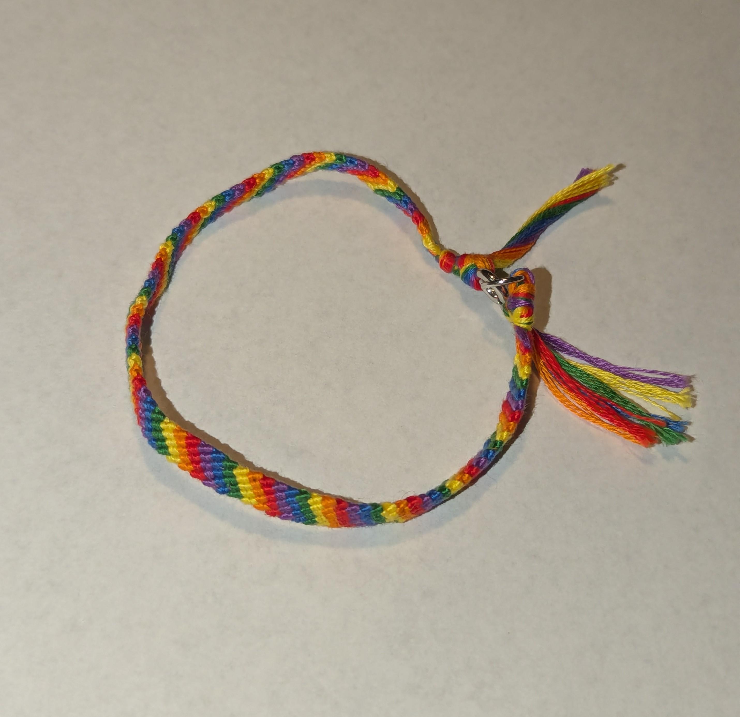 Clasped friendship bracelet with a candy stripe pattern with the colors: red, orange, yellow, green, blue, purple