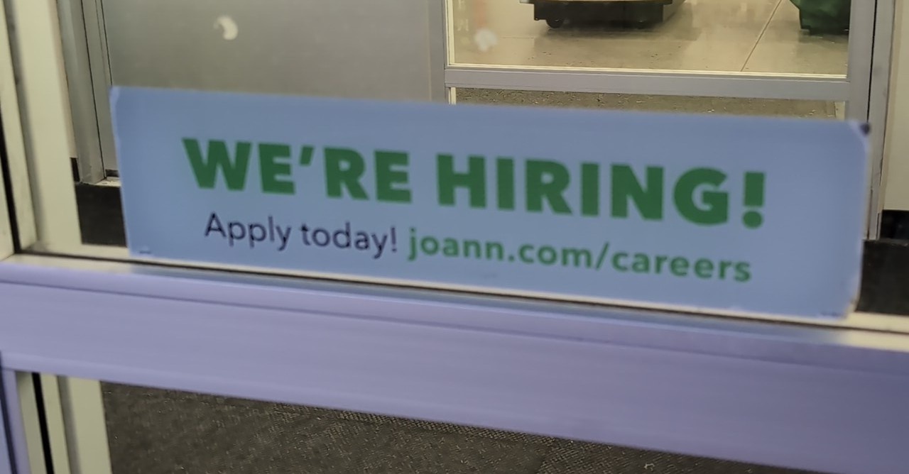 sign in a storefront reading "we're hiring! apply today! joann.com/careers"