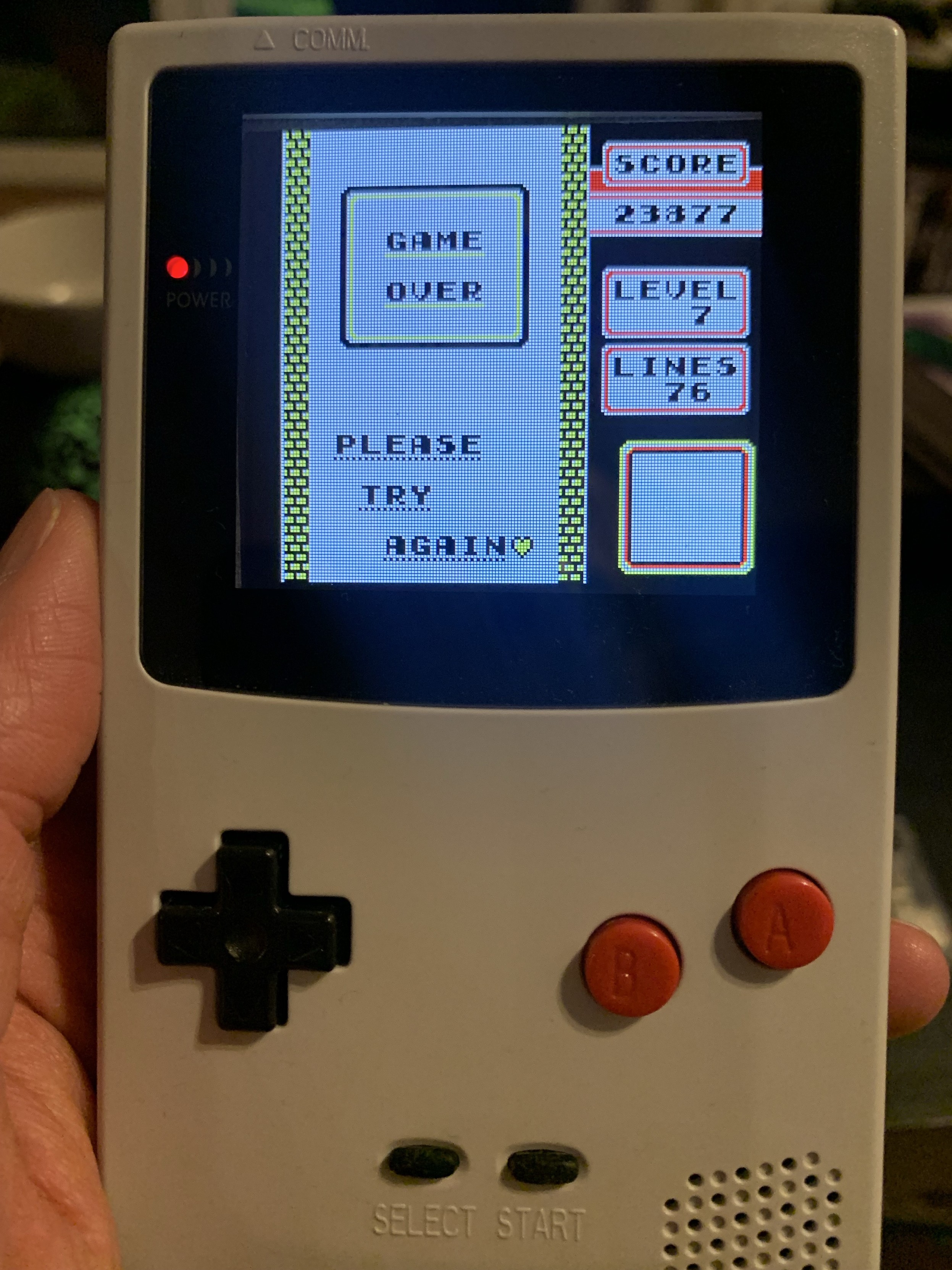 Gameboy color showing tetris game over screen with 23877 points and 76 lines in level 7. 