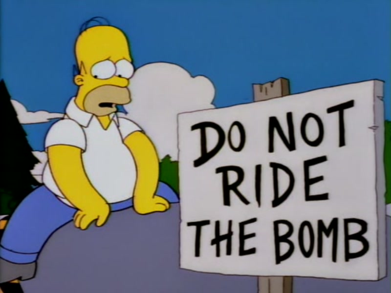 Homer Simpson riding the bomb next to a sign saying not to do so