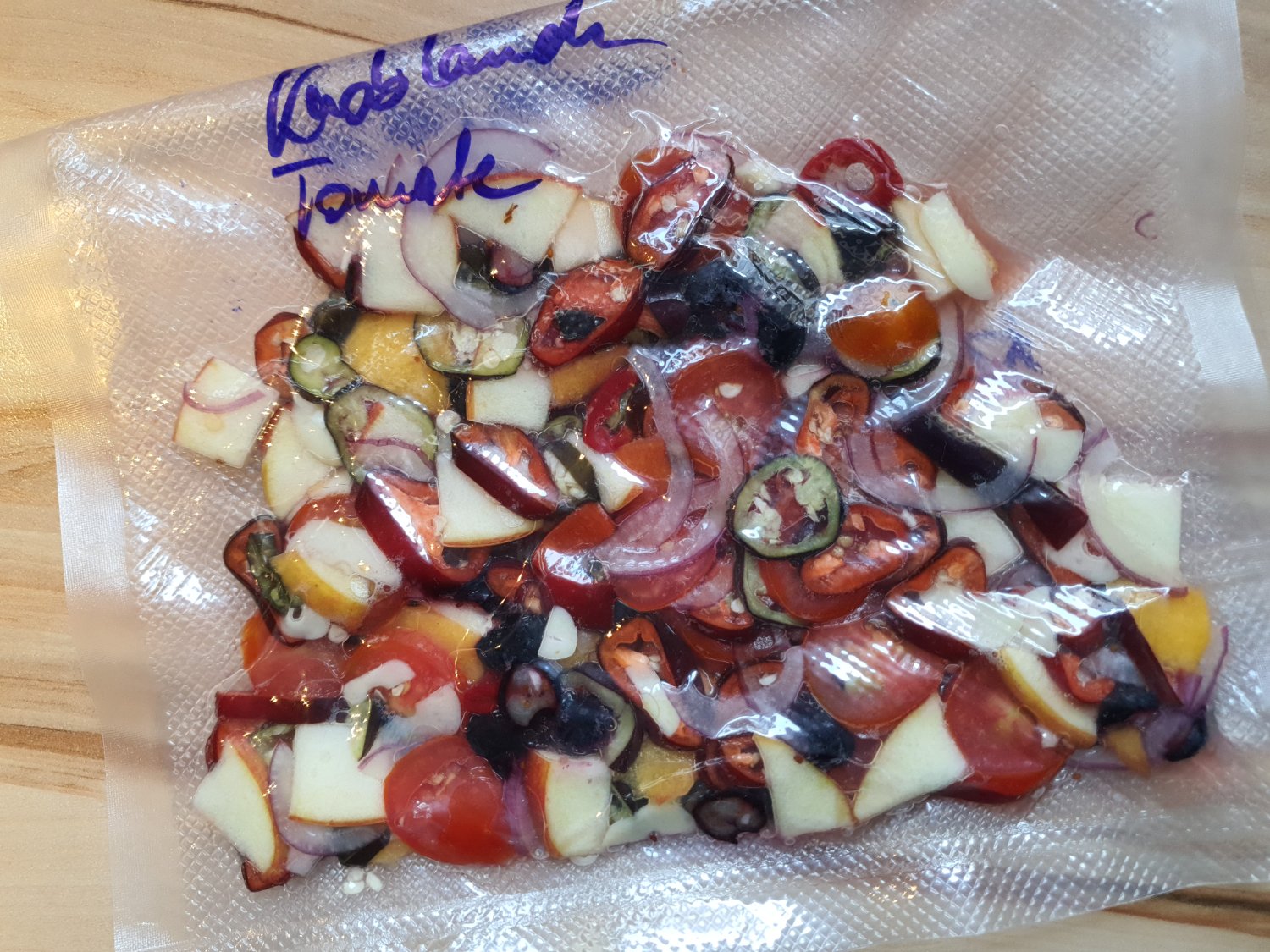 Vacuum bag wirh chilis, apple, blueberrys, tomatos, garlic and onions