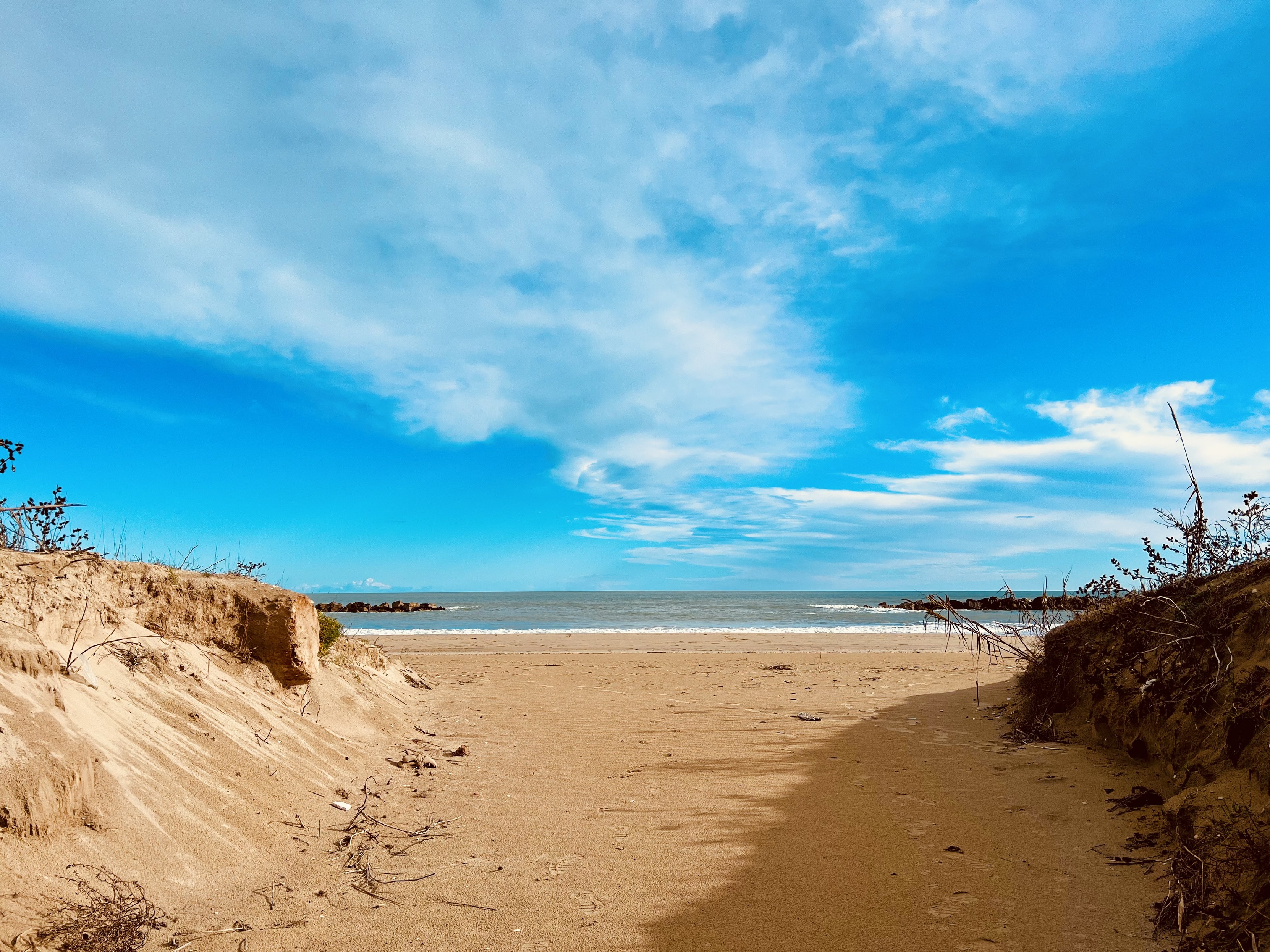 A view from a beach, with sand, blue sky and the sea. The light, the sea and the sand will shine on you, warming your soul.