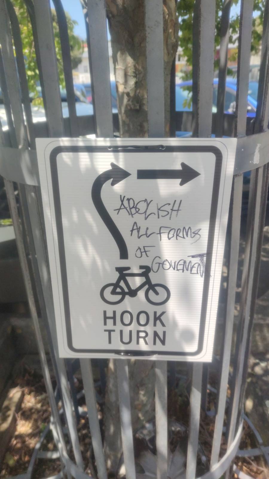 A sign for cyclists indicating to perform a hook turn with graffiti "abolish all forms of government"