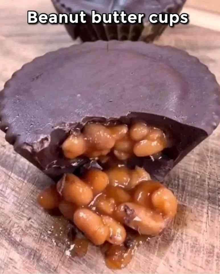 A Reeces Cup with a bite taken out. The inside is not of peanut butter as is typical of this candy, but of beans, which spill out onto the surface the “cup” is on.