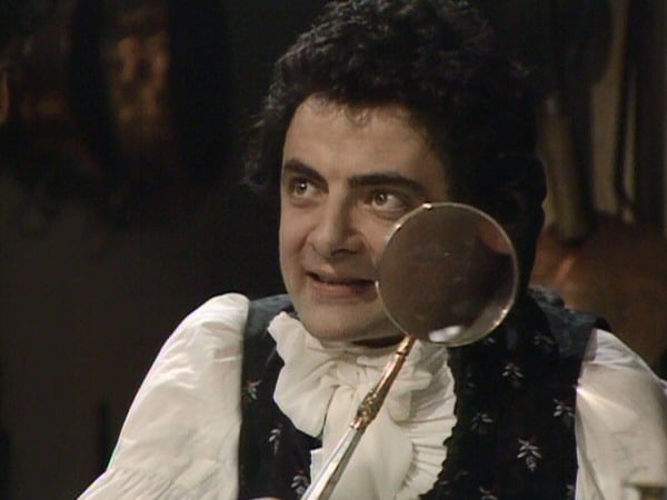 Rowan Atkinson playing Black Adder on TV with a looking glass