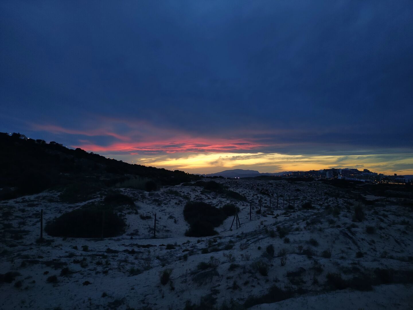 The three pictures are the same shot but different focus to get the sun set colors right. Pink, red and orange clouds above a sand dune.