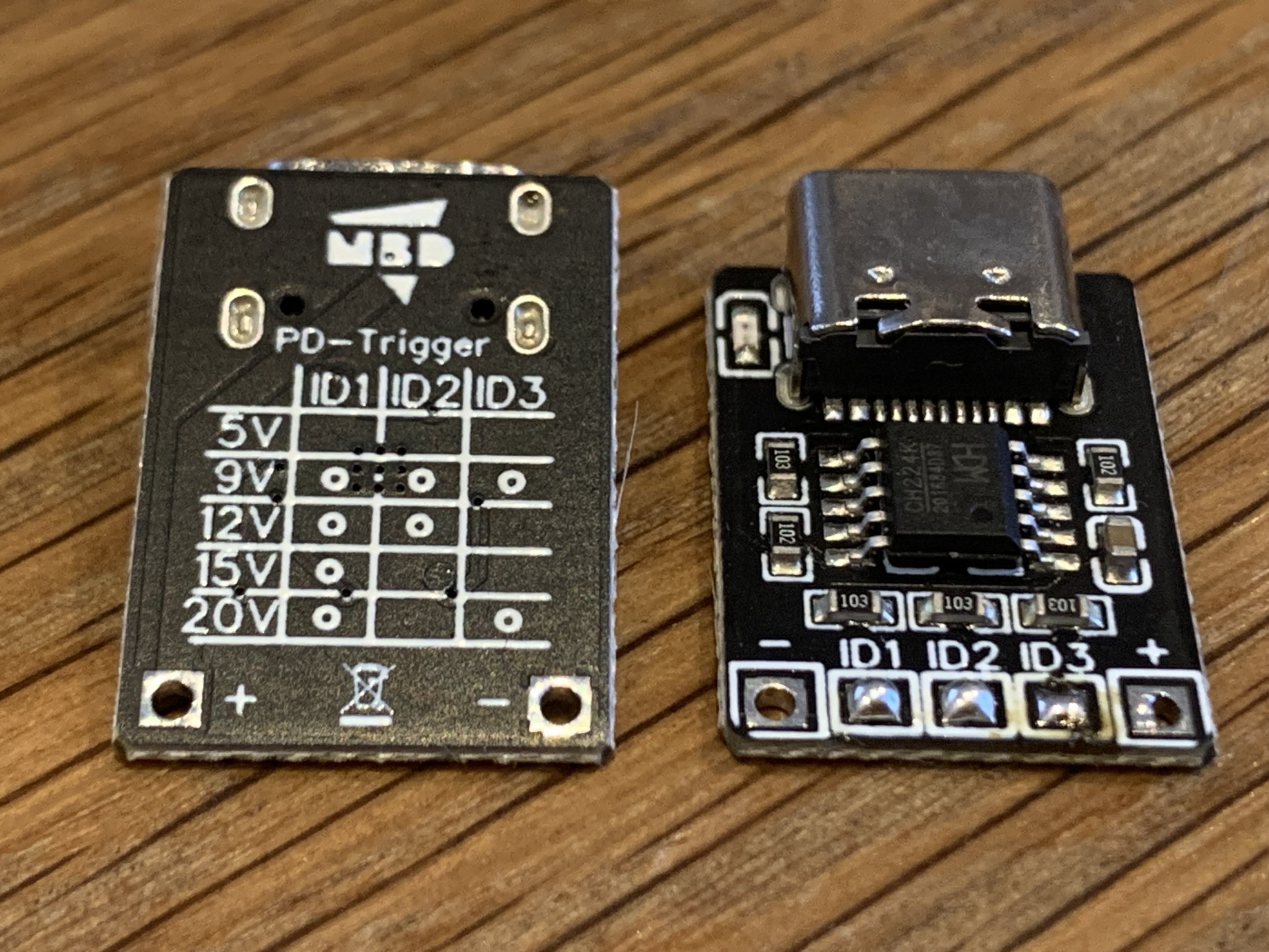 Two black PCBs. One showing the backside with jumper configurations documented in the silkscreen for selecting 5-20V. The other showing the upper side with a small SOT10 chip and a USB C socket. 